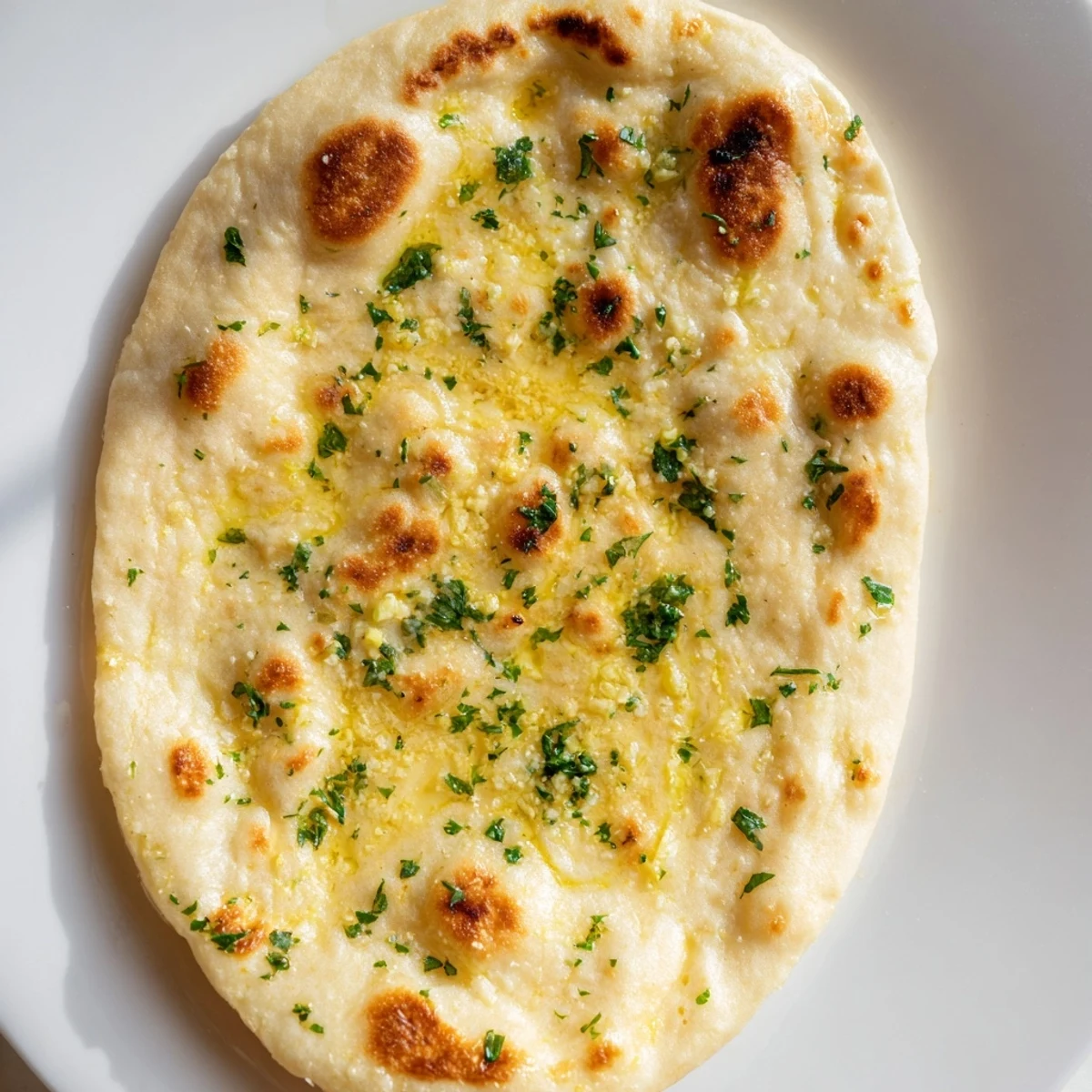 Homemade Garlic Naan Bread, golden-brown and brushed with garlic butter—ready to sop up delicious curry.