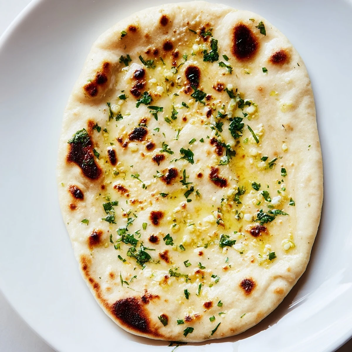 A close-up of blistered Homemade Garlic Naan Bread, showing soft texture and garlic butter glaze.