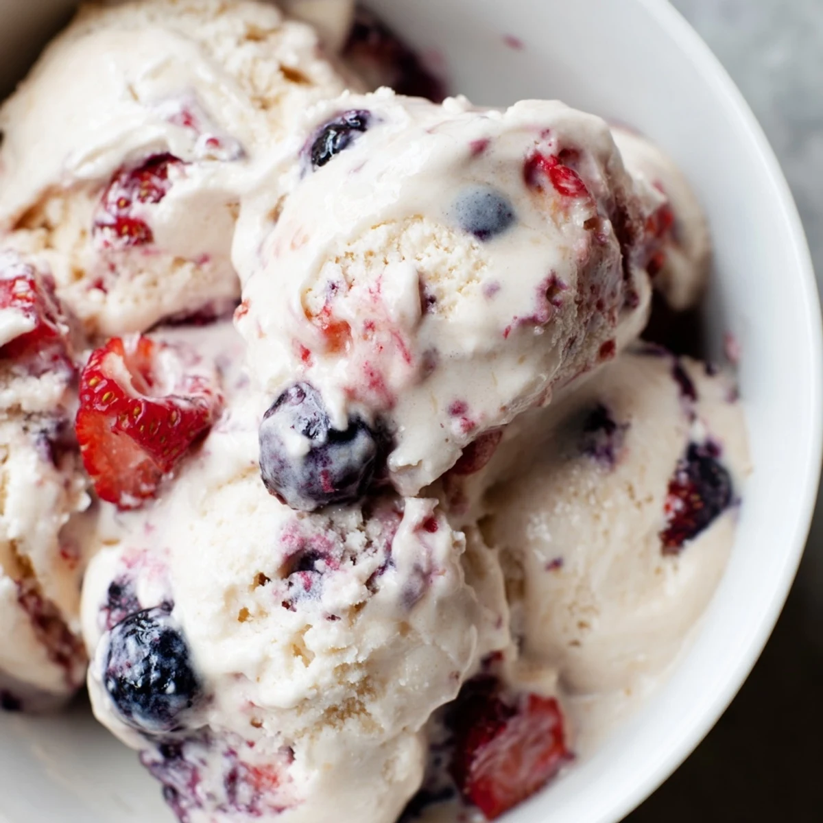 A vibrant swirl of Cottage Cheese Ice Cream, studded with frozen berries, ready to scoop.