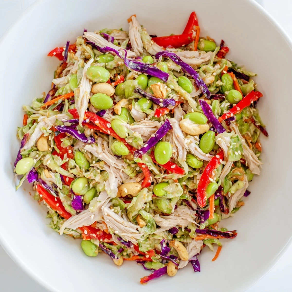 A protein-packed bowl of Edamame Crunch Chicken Salad garnished with sliced red bell pepper and green onions, ready to eat.