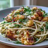 A close-up view shows the low-calorie Italian pasta dish garnished with fresh parsley and lemon zest.