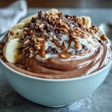 Rich Chocolate Peanut Butter Smoothie Bowl in a white bowl, featuring a drizzle of peanut butter and fresh fruit.
