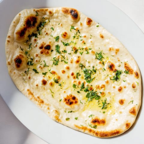 Warm, fluffy Homemade Garlic Naan Bread, aromatic with fresh garlic, awaiting a savory Indian meal.