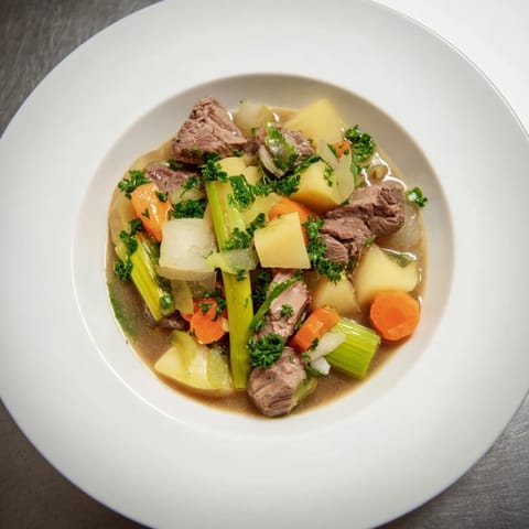 Close-up of a steaming bowl of Welsh Cawl, showcasing juicy lamb chunks and vibrant carrots.