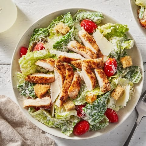 A close-up of creamy Greek yogurt Caesar dressing drizzled over tender grilled chicken in this light and refreshing Yogurt Caesar Grilled Chicken Salad.