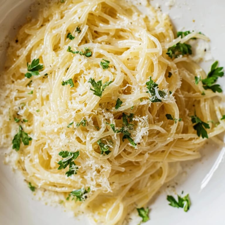 Lemon Butter Pasta Light with angel hair coated in buttery citrus, garnished with fresh parsley and a sprinkle of Parmesan cheese.