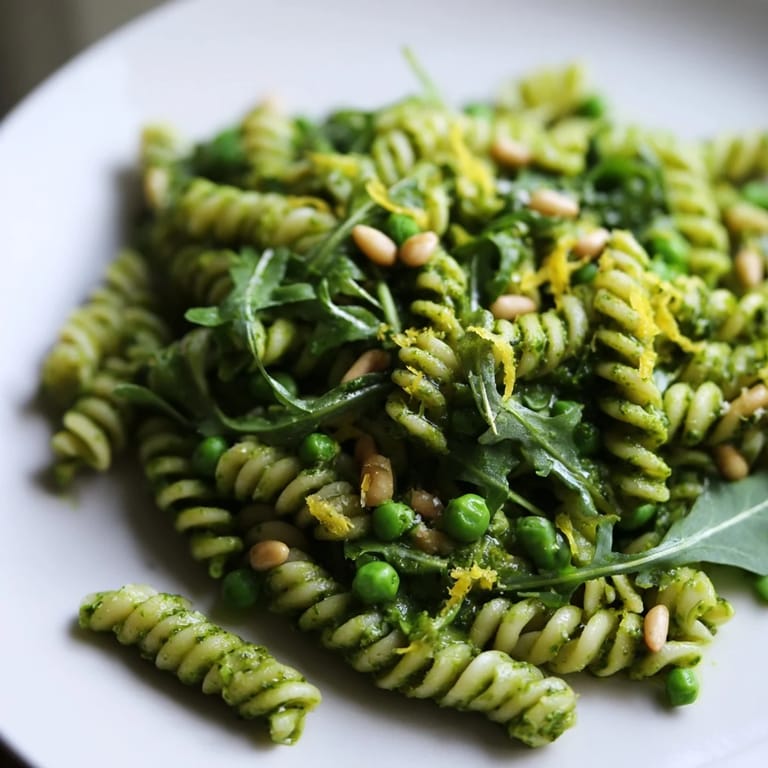 Freshly tossed Spring Green Pesto Pasta Salad with bright green basil pesto, lemon zest, and crunchy pine nuts, perfect for a spring picnic spread.