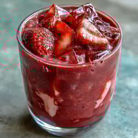 A vibrant pink drink with fresh strawberries and creamy coconut milk, perfect for a refreshing summer beverage.