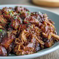 Juicy Honey Peach BBQ Pulled Pork slow-cooked to perfection in a crockpot, topped with sweet peaches and tangy sauce.  