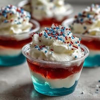 Colorful 4th of July Firecracker Jello Shots, layered red, white, and blue, ready for celebration.